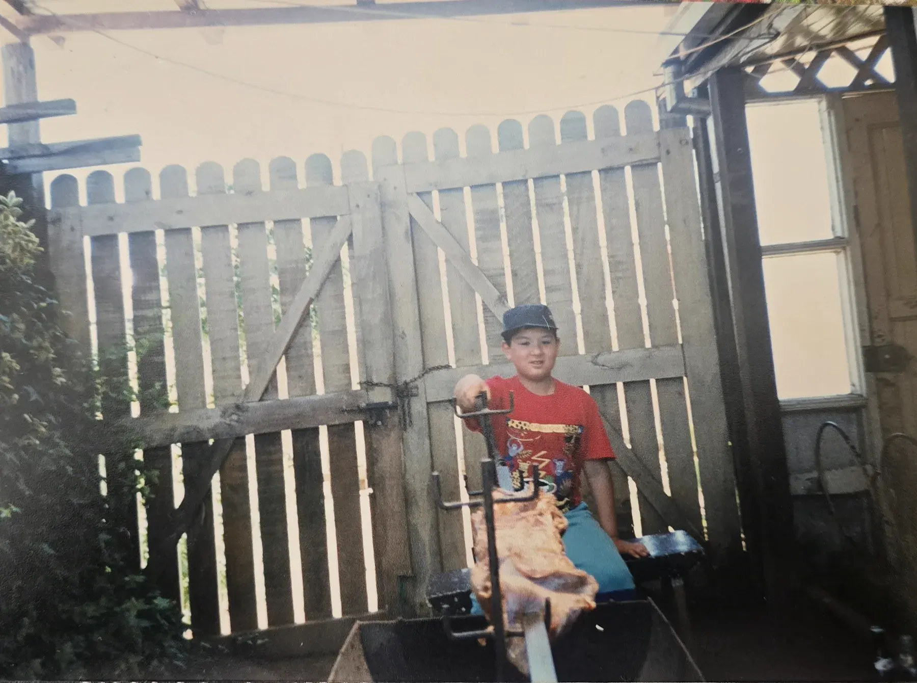 Gustavo de niño, sentado junto a un asado al palo
